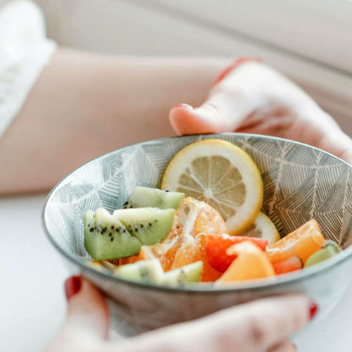 woman's hands holding a bowl of fruit salad