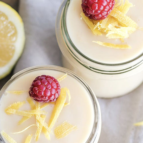 top view of pale yellow desserts in glass bottles topped with a raspberry